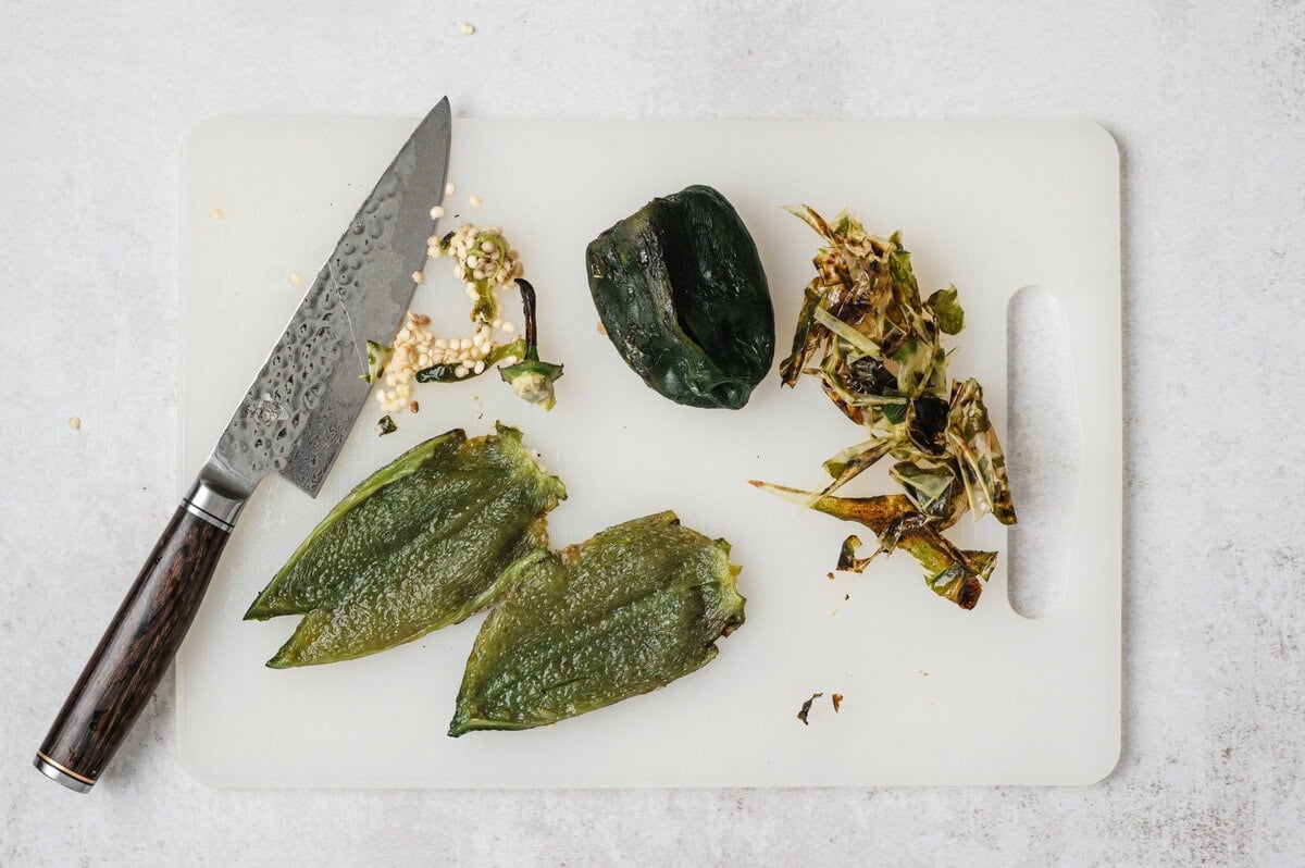 Chile being peeled and sliced on a cutting board.