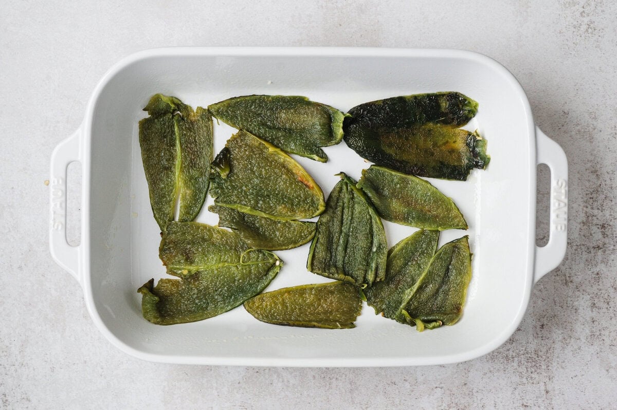 Poblano peppers spread out in a white casserole dish.