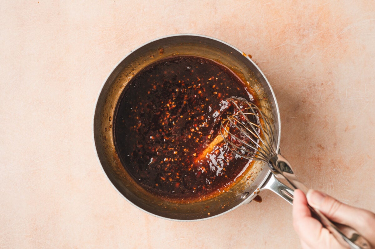 Honey garlic sauce being whisked in a saucepan