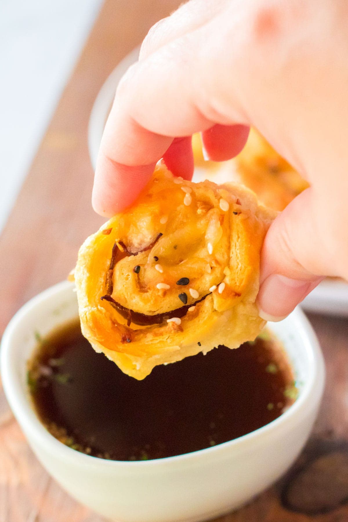 French dip pinwheel being dipped in a small dish of au jus