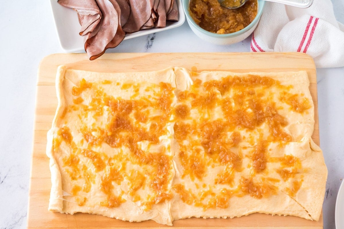 Caramelized onions spread out on crescent roll dough.