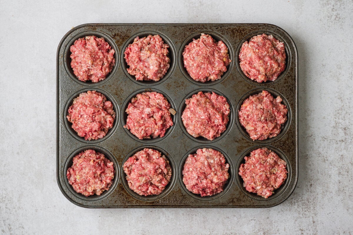 Mini meatloaves (raw) in a muffin tin, ready to bake.