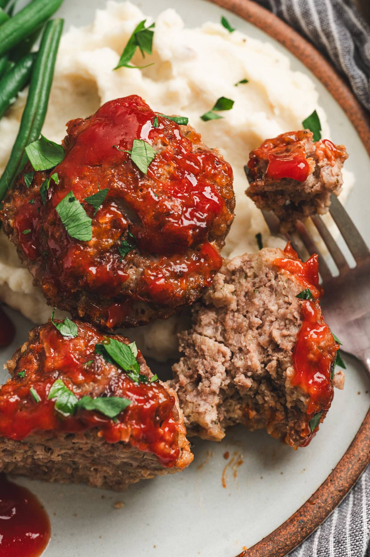 Close up of mini meatloaves on a plate, cut open to show texture inside.