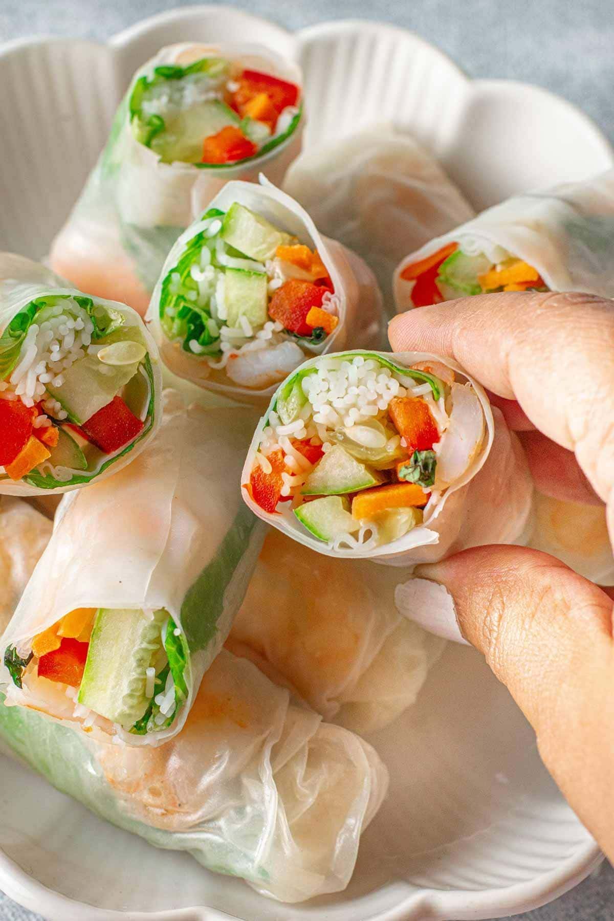 Hand holding up spring rolls to show the inside