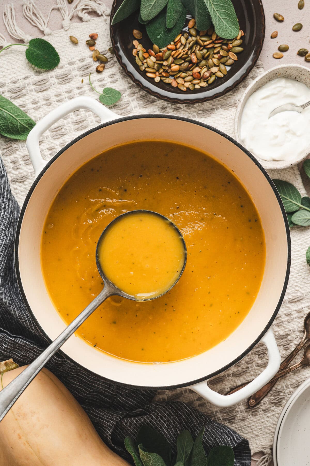 Butternut squash soup in a white pot with a serving spoon
