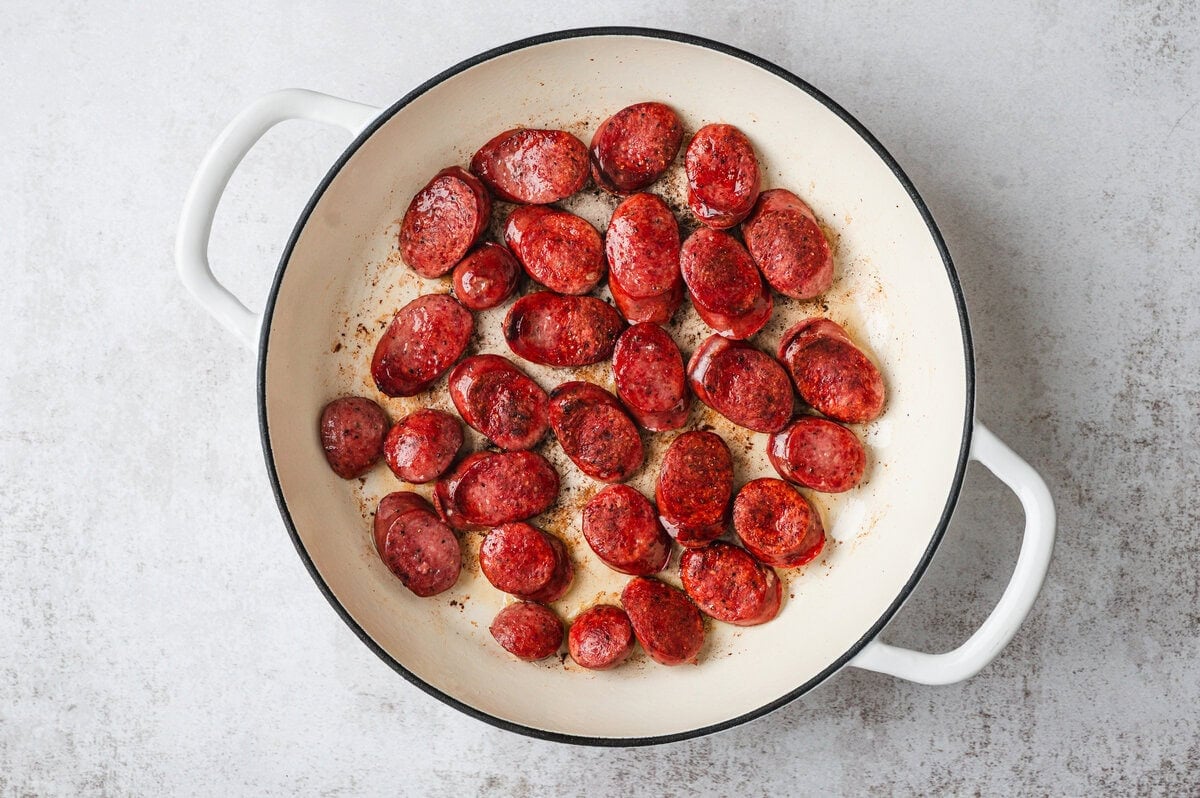 Pieces of smoked sausage being browned in a pan